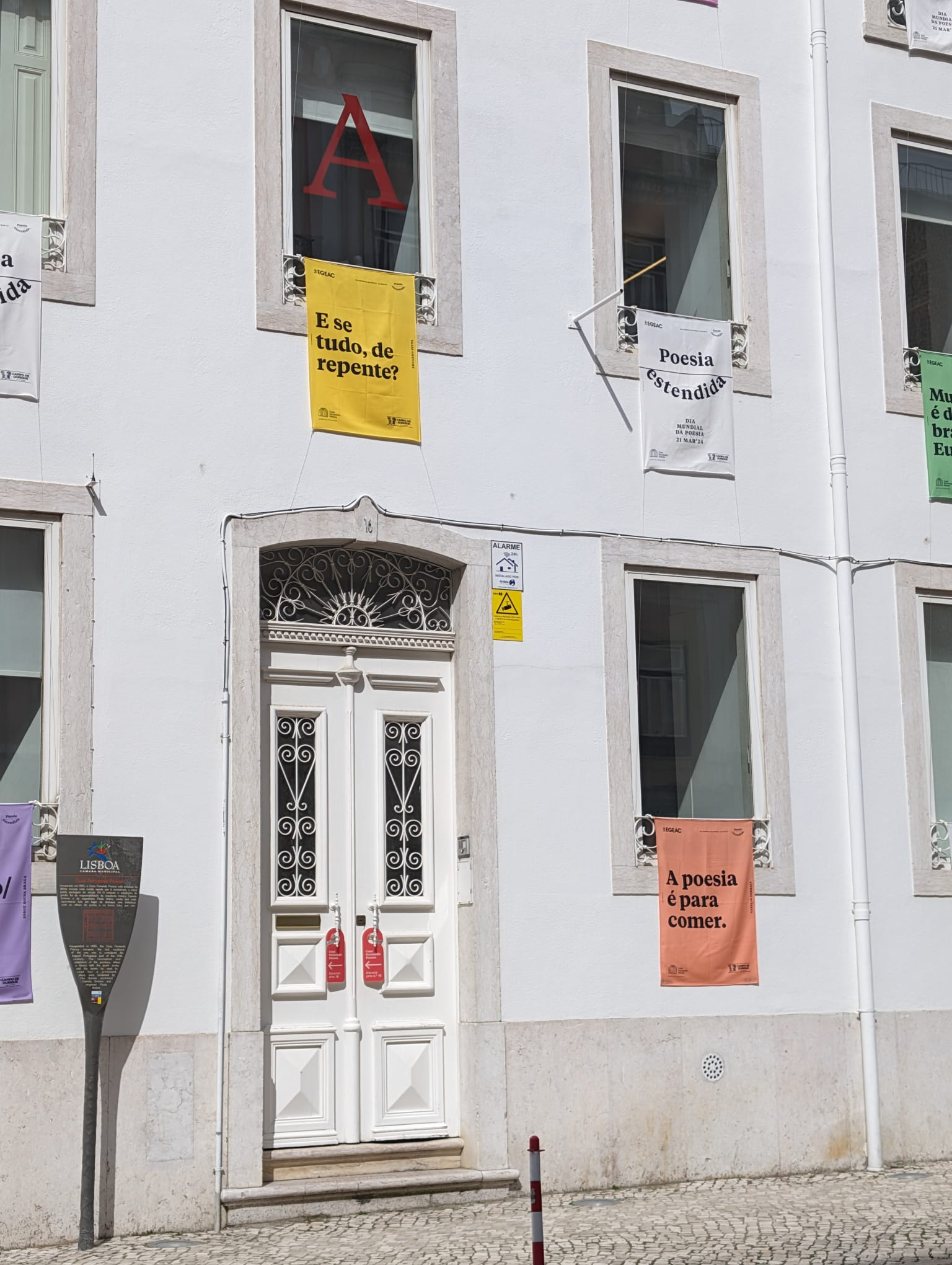 Fachada da Casa Fernando Pessoa, em Campo de Ourique, com bandeiras poéticas da iniciativa Poesia Estendida 2024